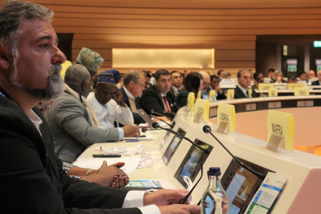 Міжнародні делегати за робочими столами під час Forum of Mayors у Женеві